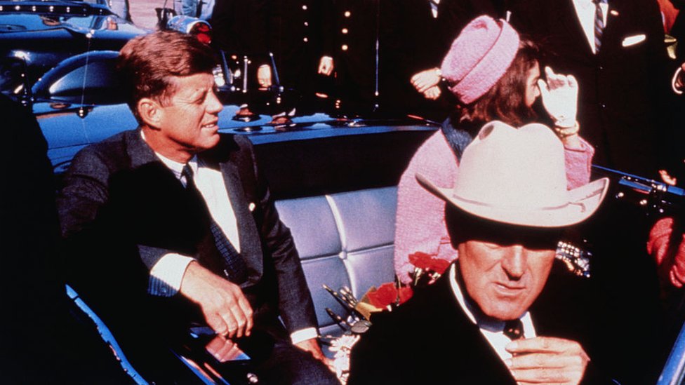 Teksaški guverner Džon Konali u prvom planu namešta kravatu dok američki predsednik Džon Kenedi (levo) i Džeki Kenedi (desno) sede na zadnjem sedištu, 22. novembar. Posle nekoliko stajanja zbog govora predsednik je ubijen u istim kolima.
