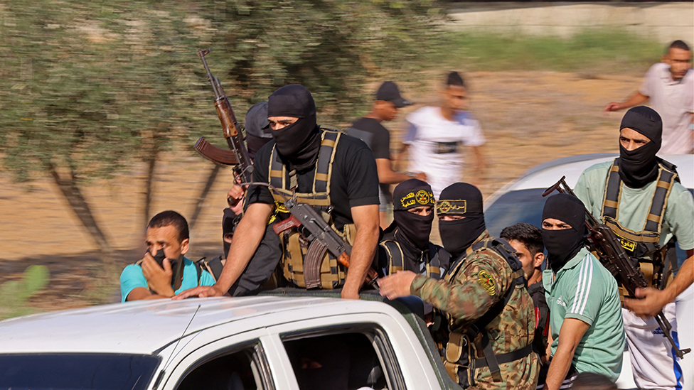 A group of militants advance towards the Israeli border from southern Gaza, in the back of a truck with guns and masks