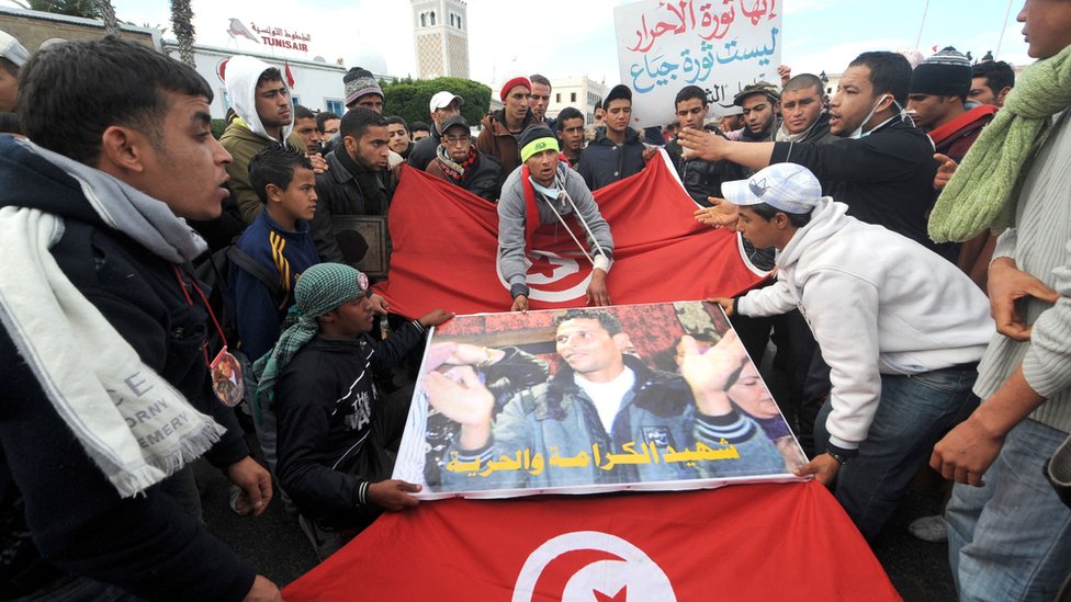 Izrael i Palestinci: Bajdenova potraga za rešenjem na Bliskom istoku upravo je postala teža - Džeremi Bouen 4 People walk with Mohamed Bouazizi poster and Tunisian flag in front of the government palace in Tunis on January 28, 2011.