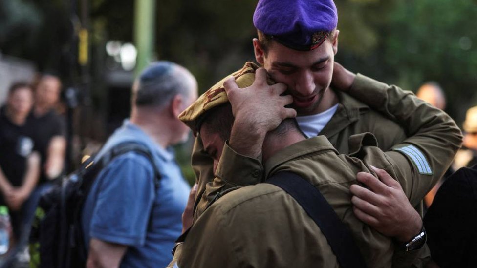 Izrael i Palestinci: Bajdenova potraga za rešenjem na Bliskom istoku upravo je postala teža - Džeremi Bouen 3 Israeli soldiers embrace as they mourn a fellow soldier