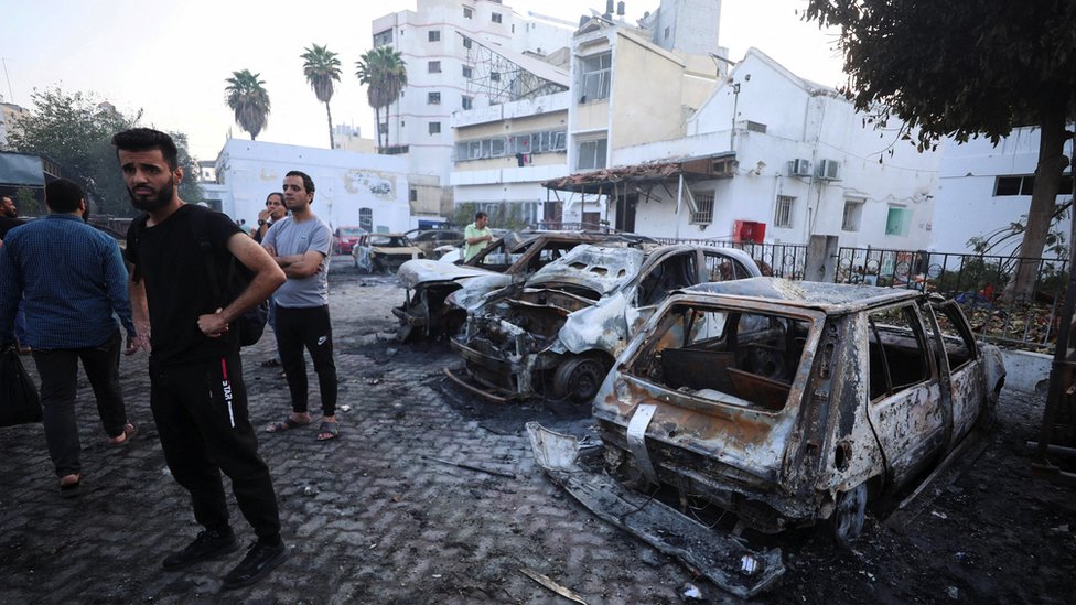 Izrael i Palestinci: Zašto još nije pokrenuta invazija izraelske vojske na Pojas Gaze 2 People inspect Al-Ahli hospital with burned out vehicles in the foreground