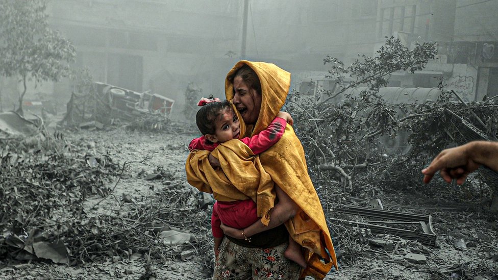 A woman holding a girl reacts after Israeli airstrikes hit Ridwan neighborhood of Gaza City, Gaza on October 23, 2023.