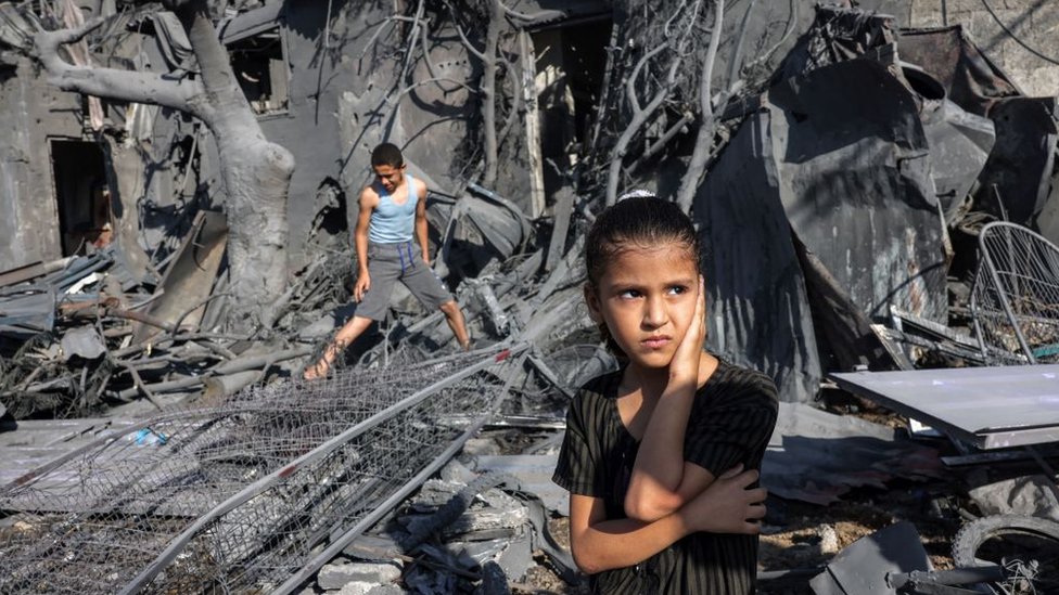 Two children stand in a devastated building in Gaza