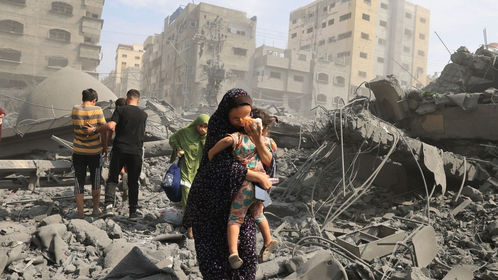 Woman and child amongst ruined buildings in Gaza