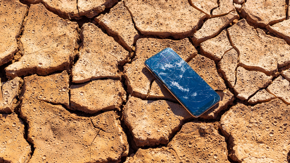 Smartphone with broken screen on dry ground