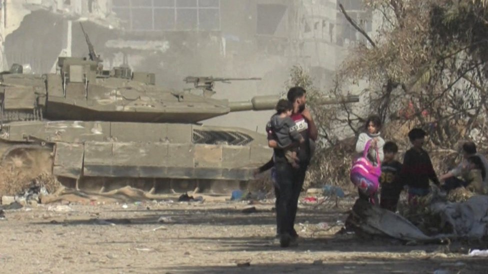 Izrael i Palestinci: Glavna bolnica u Gazi je „zona smrti", kažu UN 2 people leave shif with tank in background