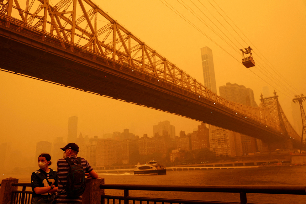 2023. godina u fotografijama: Zemljotresi, ratovi, protesti, vulkani - neverovatni kadrovi iz celog sveta 11 People wear protective masks as the Roosevelt Island Tram crosses the East River while haze and smoke from the Canadian wildfires shroud the Manhattan skyline in the Queens Borough New York City, U.S., June 7, 2023.