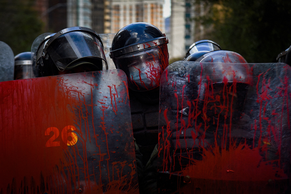 Police officers stand guard with their shields covered in red paint during a protest held by teachers against a new curriculum established by Bolivia's Ministry of Education, in La Paz, Bolivia, April 10, 2023.