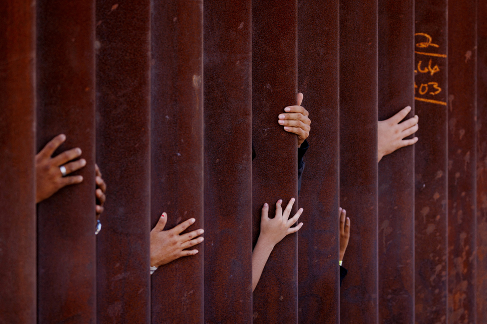 2023. godina u fotografijama: Zemljotresi, ratovi, protesti, vulkani - neverovatni kadrovi iz celog sveta 18 Migrants wait for some food from an aid worker after gathering between the primary and secondary border fences between Mexico and the United States as they await processing by U.S immigration in San Diego, USA. September 12, 2023.