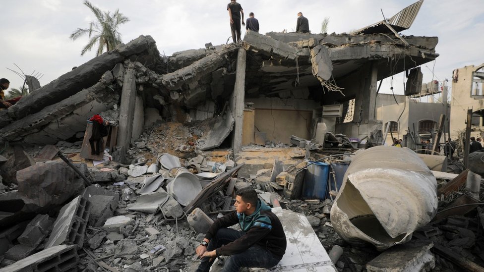 Izrael i Palestinci: Četvorogodišnji Omar ostao bez roditelja i bez ruke 2 Palestinians search for casualties beneath the rubble of a building destroyed in an Israeli air strike in Deir al-Balah, in the central Gaza Strip (8 December 2023)