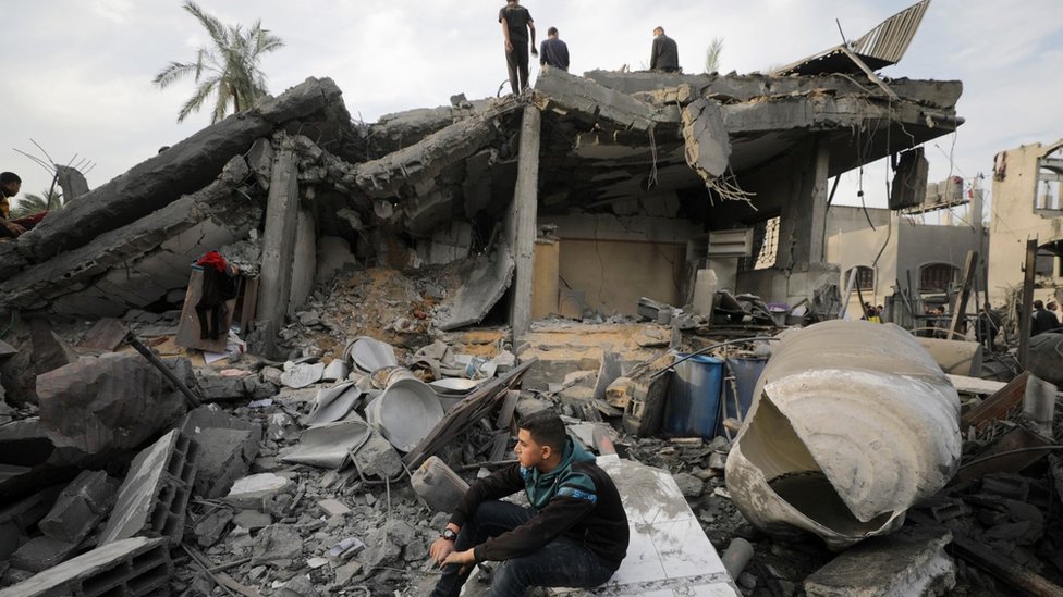 Palestinians search for casualties beneath the rubble of a building destroyed in an Israeli air strike in Deir al-Balah, in the central Gaza Strip (8 December 2023)