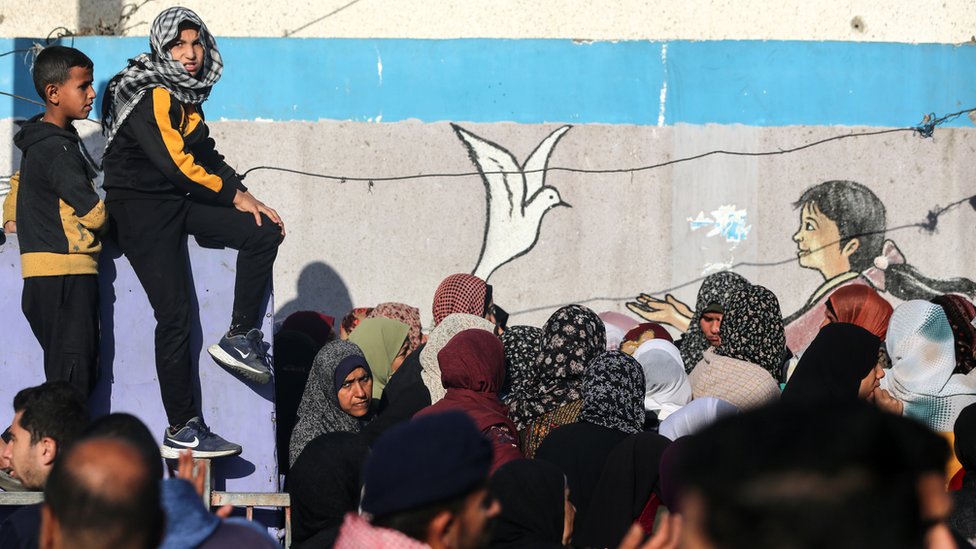 Palestinians queue for food aid at a UN distribution centre in Deir al-Balah, in central Gaza (10 December 2023)