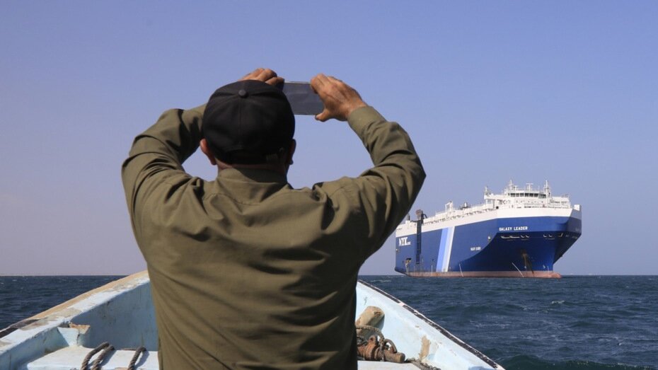epa11012839 A Yemeni sitting on a boat uses a mobile phone to film the Galaxy Leader cargo ship, seized by the Houthis offshore of the Al-Salif port on the Red Sea in the province of Hodeidah, Yemen, 05 December 2023. The Galaxy Leader ship, reportedly linked to an Israeli businessman, was seized and re-routed to offshore of the Yemeni port of Al-Salif by the Houthis on 19 November 2023 in retaliation for Israel's airstrikes on the Gaza Strip, according to statements by the Houthis. The ship, carrying around 25 crew members belonging to various nations, was seized as it was on its way to India. The Houthis, who control most of Yemen 's Red Sea coast, have fired missiles and drones at Israel and attacked more vessels transiting the area. Thousands of Israelis and Palestinians have died since the militant group Hamas launched an unprecedented attack on Israel from the Gaza Strip on 07 October, and the Israeli strikes on the Palestinian enclave which followed it. 