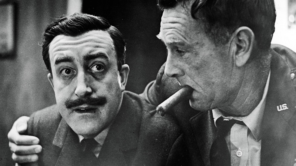 Sterling Hayden (right) as General Jack Ripper, holds a cigar in his mouth and puts his arm around Peter Sellers, as Group Captain Lt. Mandrake, in a still from the Stanley Kubrick directed film Dr. Strangelove: Or How I Came to Stop Worrying and Love the Bomb