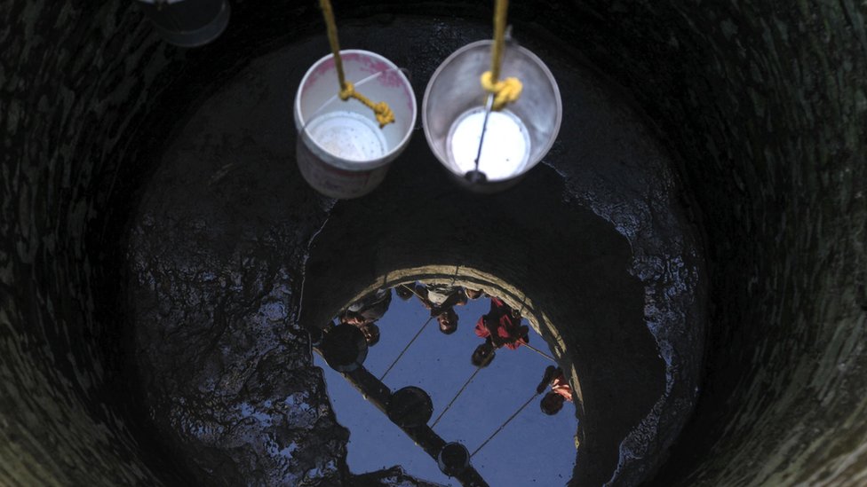 Two buckets are lowered into a well