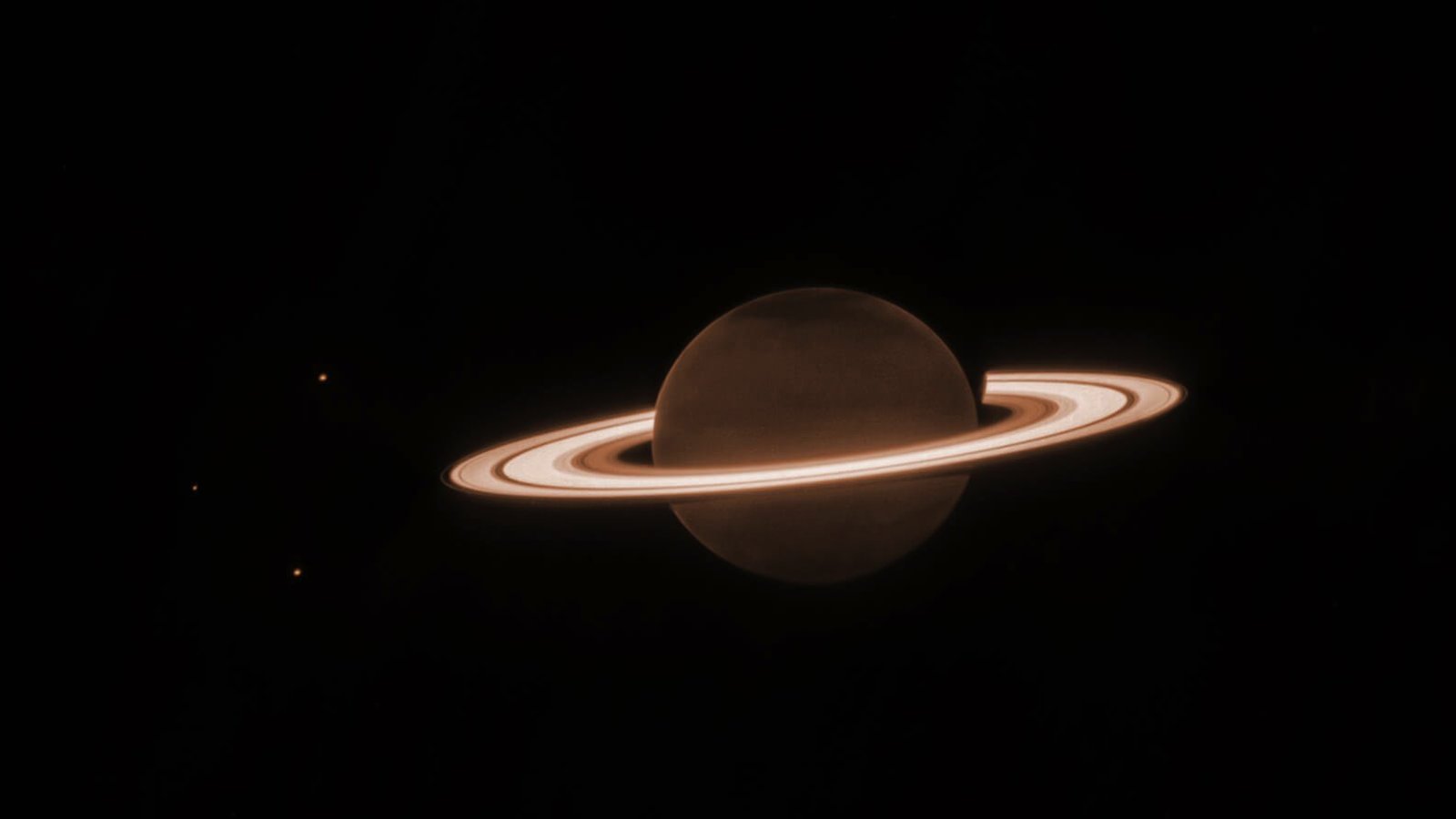 The ringed orb of Saturn appears bather in a brown/orange glow