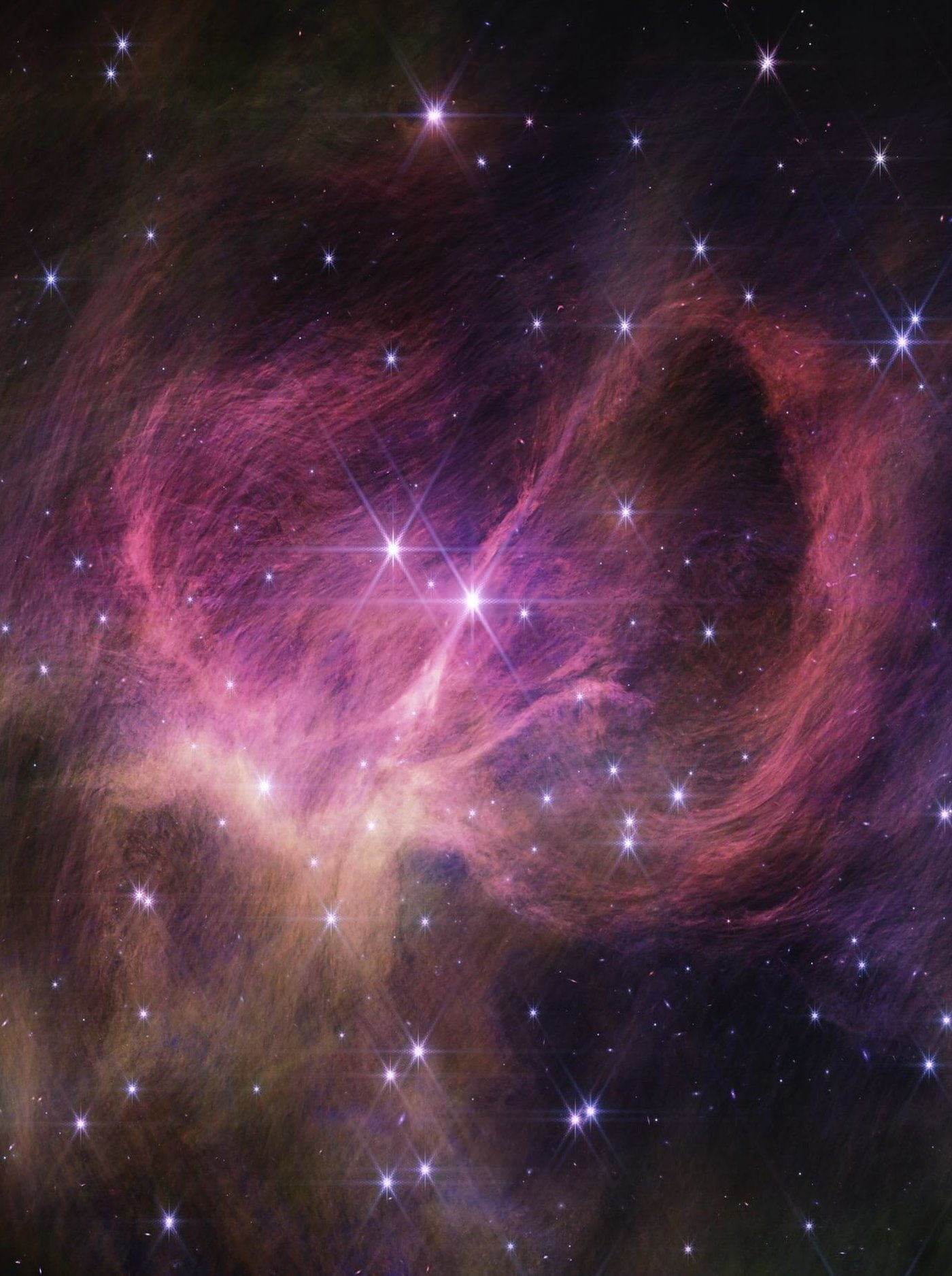 Orange and pink wisps of gas and dust stream between stars