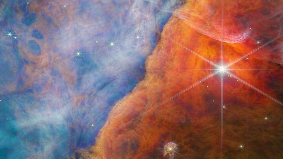 Stars shine through a sandy coloured nebula in an image taken by the JWST