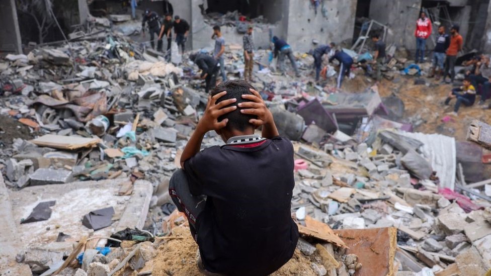 A child reacts as people salvage belongings amid the rubble of a damaged building following strikes on Rafah in the southern Gaza Strip in November