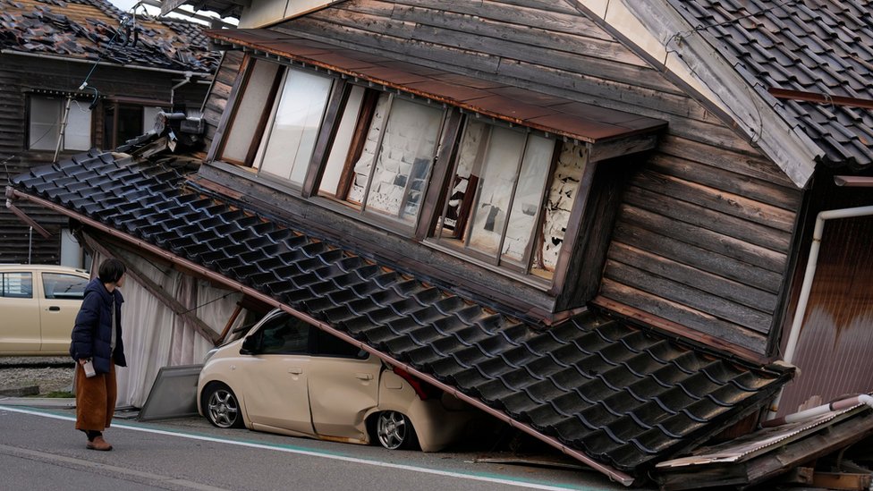 A woman walks past a collapsed house on the Noto peninsula - the epicentre of the quake