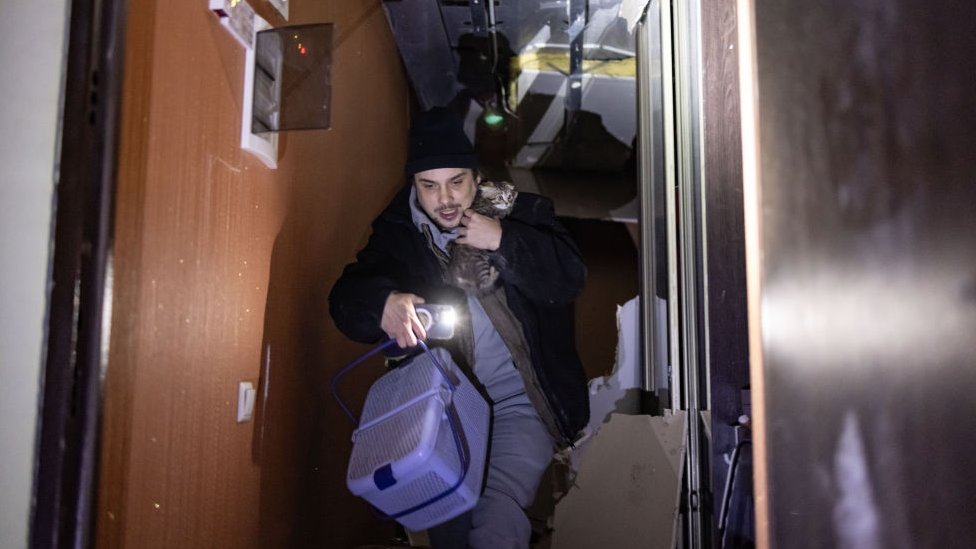 A man rescues his cat in a block of flats after a Russian attack on the Ukrainian city of Kharkiv