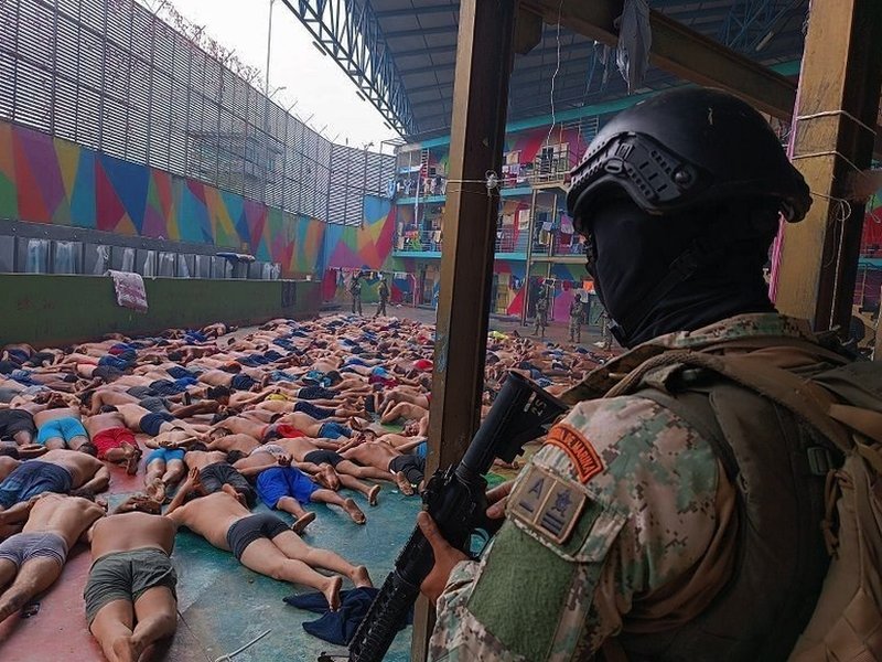 Ekvador i kriminal: Tri ključne tačke koje objašnjavaju „unutrašnji oružani sukob“ 5 A soldier stands guard over dozens of prisoners, lying face down in a prison courtyard