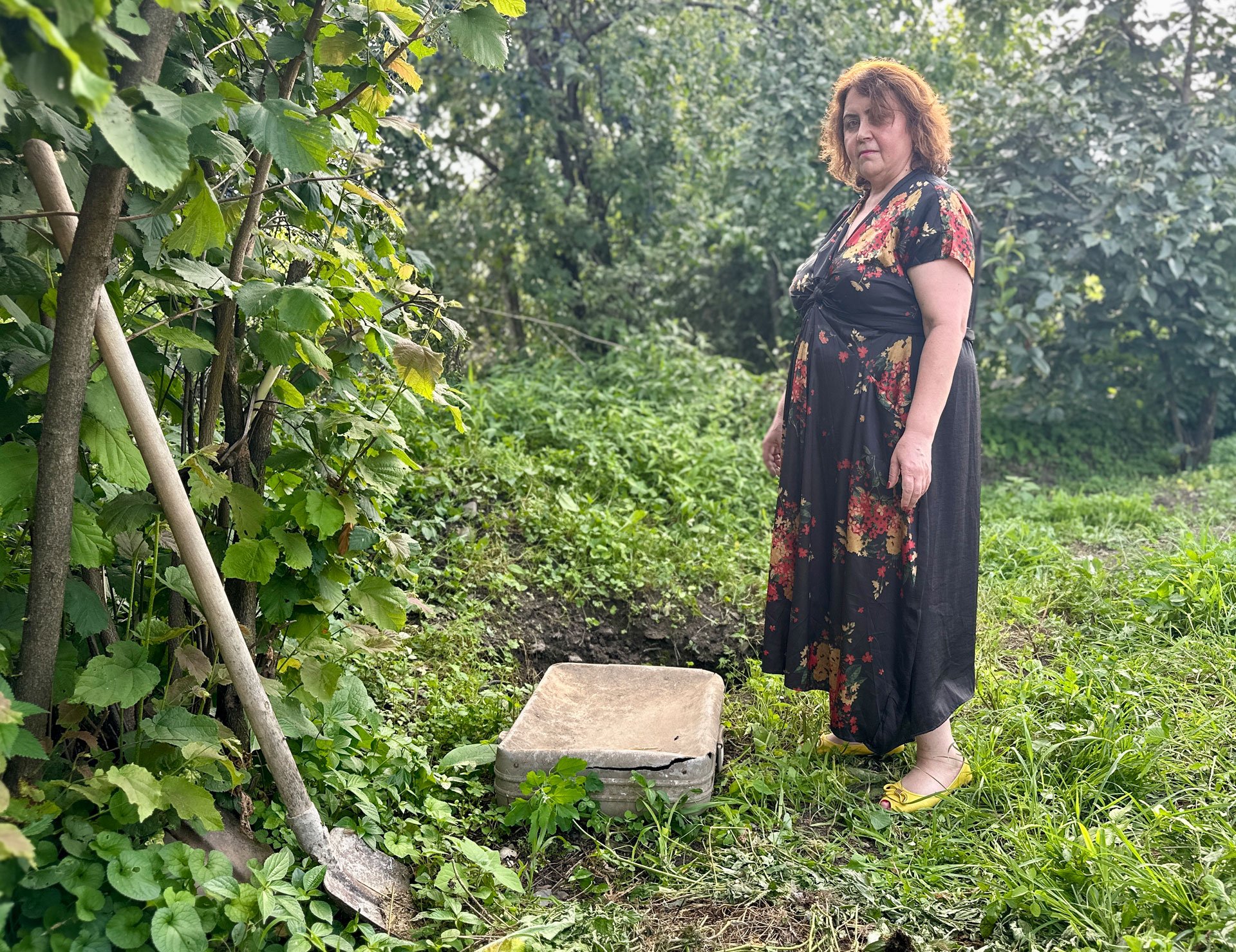 Vajza e Irinës Nino Elizbarashvili qëndron pranë një valixhe dhe një lopatë në kopsht