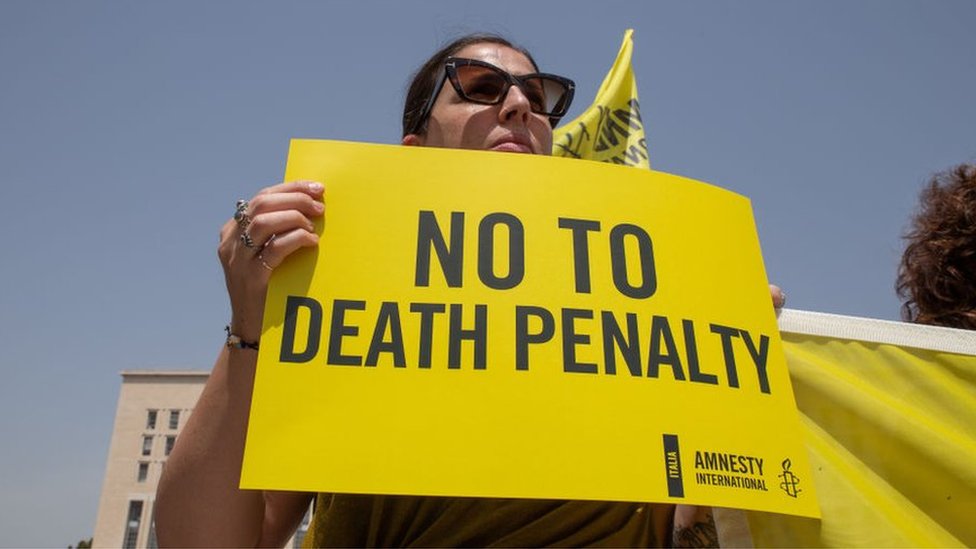 A protestor holds an Amnesty International sign reading "No to death penalty"