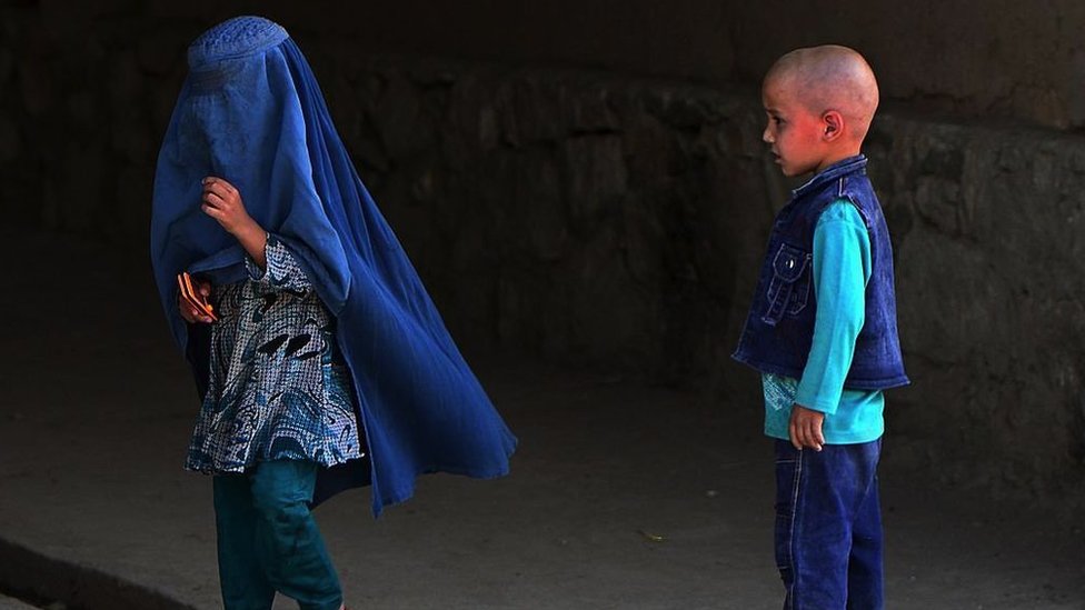 A boy looks at a young girl wearing a burka