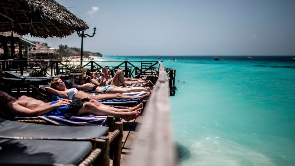 Tourists sunbath on deckchair at an hotel on Nungwi Beach, on the island of Zanzibar,on December 30, 2017.