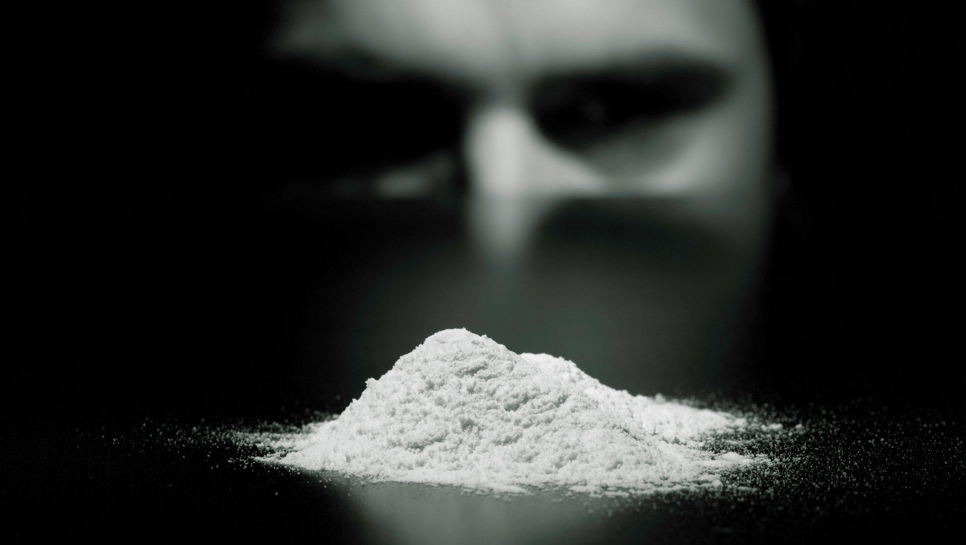 A pile of white powder with a blurred face in the background