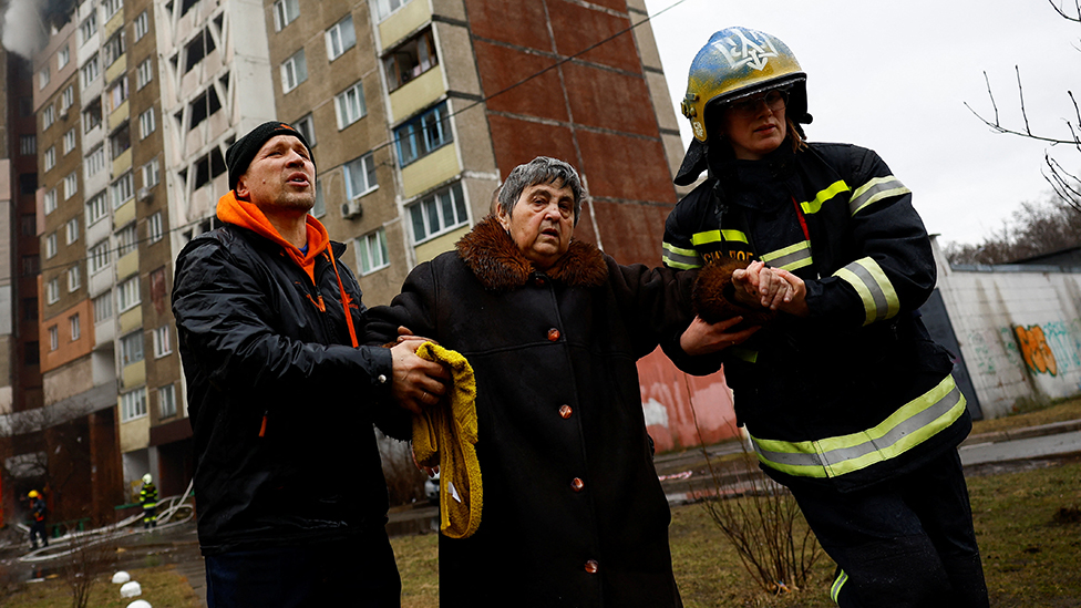 Rusija i Ukrajina: Troje ljudi poginulo, a 11 ranjeno u ruskom napadu na Kijev i Nikolajev 2 Firefighters help a woman from a building damaged during a Russian missile strike, amid Russia's attack on Ukraine, in Kyiv, Ukraine February 7, 2024