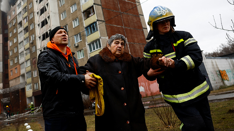Firefighters help a woman from a building damaged during a Russian missile strike, amid Russia's attack on Ukraine, in Kyiv, Ukraine February 7, 2024