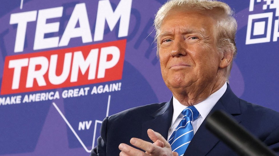 Amerika i politika: Vrhovni sud odlučuje da li Tramp može da se kandiduje za predsednika 1 Donald Trump in front of a sign that reads "Team Trump"