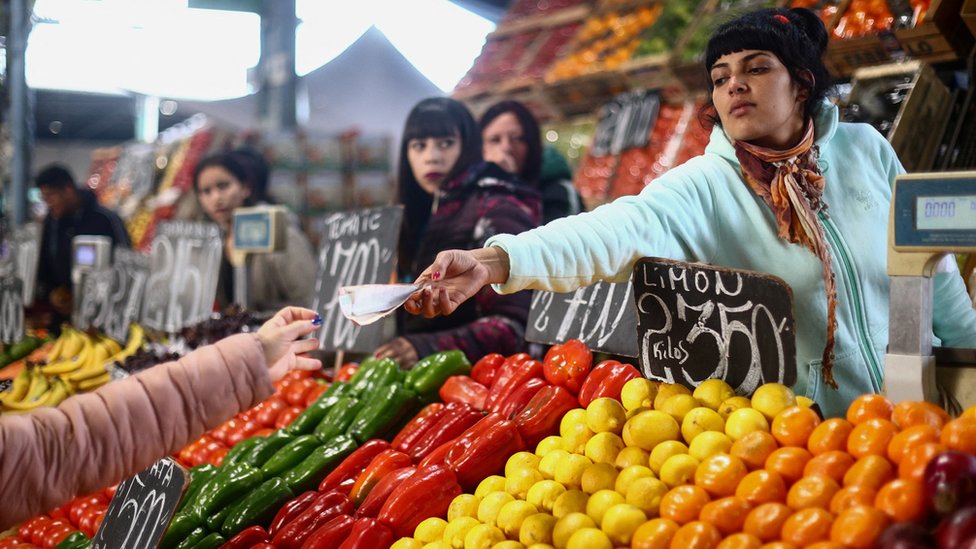 Havijer Milei: Argentinci čekaju da proradi šok terapija „ludog“ predsednika 3 A saleswoman gives change to a customer at a greengrocer's shop in Buenos Aires