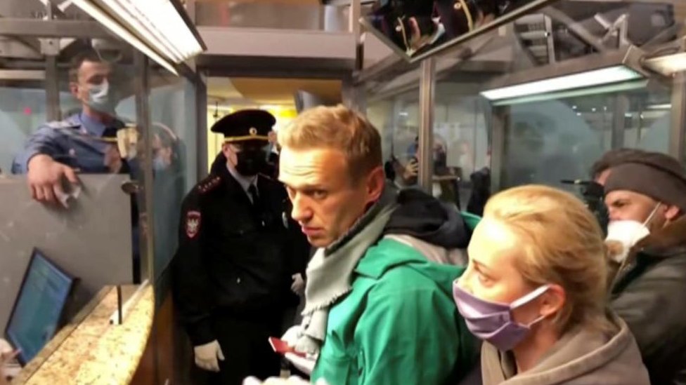 Law enforcement officers speaking with Russian opposition leader Alexei Navalny before leading him away at Sheremetyevo airport in Moscow, Russia January 17, 2021