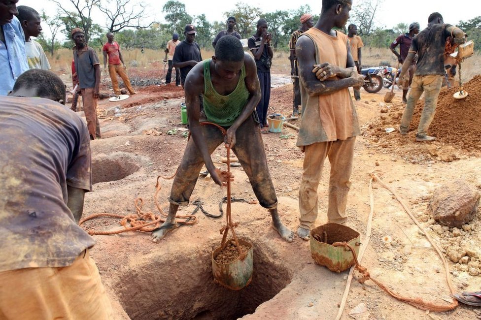 Minatorët e arit zbrazin kontejnerët e tokës, të hequra nga një bosht minierash në Koflatie, Mali, më 28 tetor 2014, një minierë e vendosur disa milje larg kufirit me fqinjin e saj jugperëndimor Guinea.