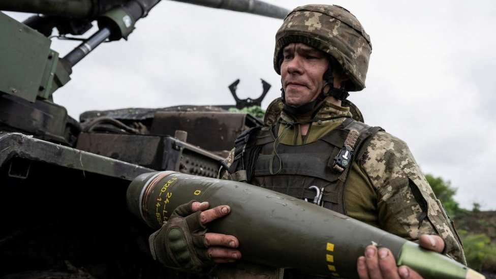 Ukrajinski vojnik nosi artiljerijsku granatu. Fotografija datoteke