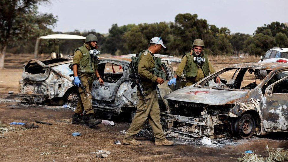 Israeli troops inspect brunt cars in the aftermath of Nova festival attack