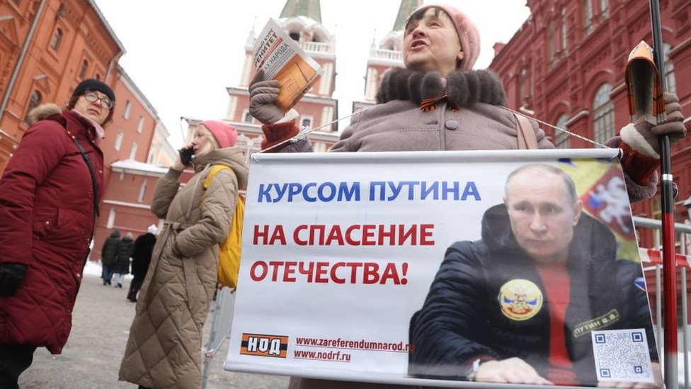 Izbori u Rusiji: Kontrolisano glasanje koje će Putinu doneti peti mandat 4 A Putin supporter holds a poster in Red Square ahead of the 2024 election