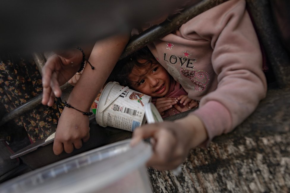 Palestinska deca stoje u redu za hranu na punktu za pomoć u Gazi
