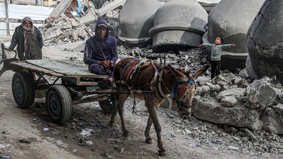 A man drives a donkey-pulled cart past the rubble of Al-Faruq Mosque, that was destroyed during Israeli bombardment, in Rafah