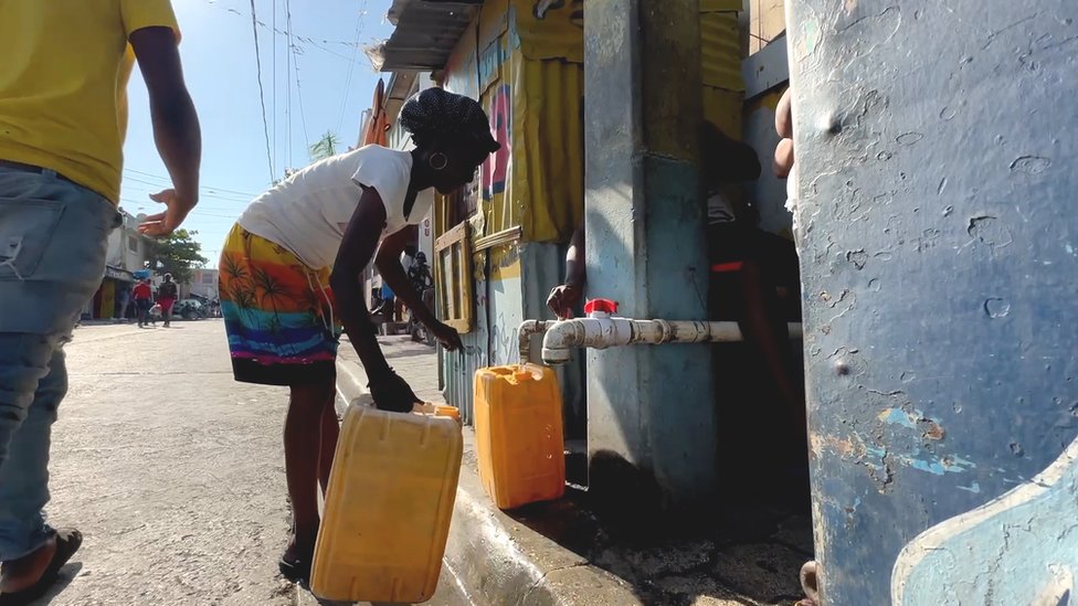 A woman collects water in Haiti in March 2024