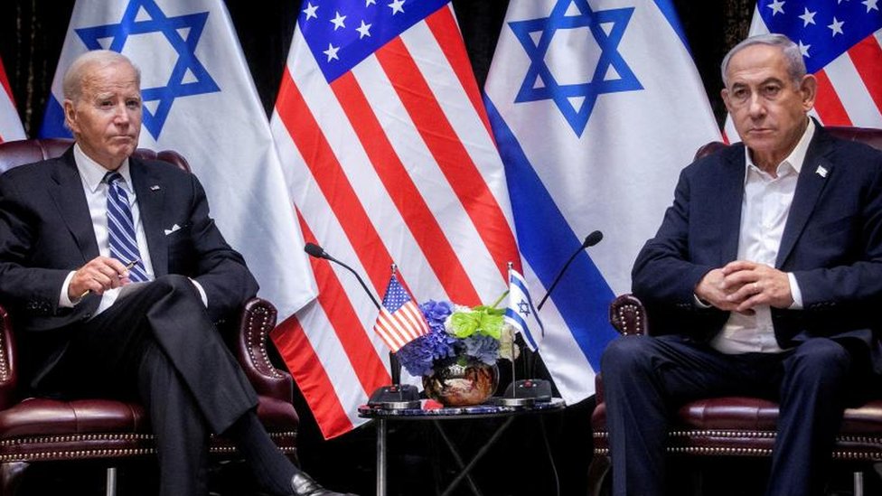 US President Joe Biden and Israel Prime Minister Benjamin Netanyahu seated next to each other at a press conference. American and Israeli are lined up in the background