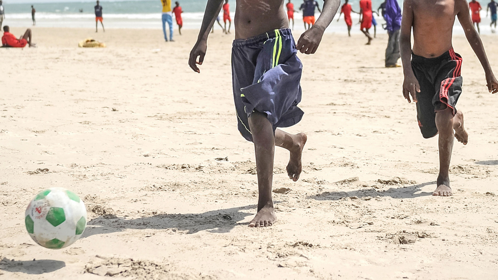 Somalija: Stratište na peščanoj plaži koje služi kao fudbalski teren 1 Boys playing football on a beach in Mogadishu, Somalia