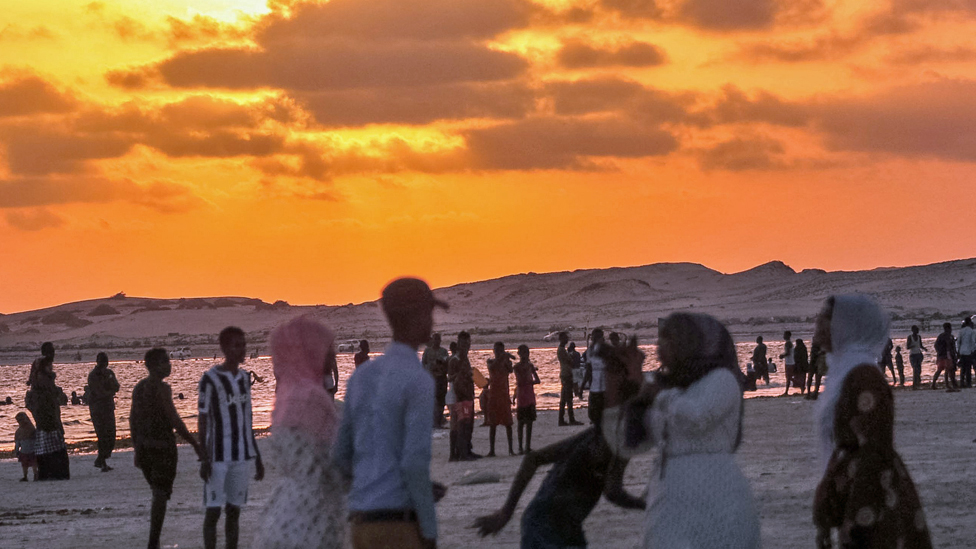 Somalija: Stratište na peščanoj plaži koje služi kao fudbalski teren 4 People at sunset on a beach in Mogadishu, Somalia