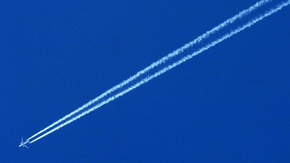 An airplane trailed by a contrail