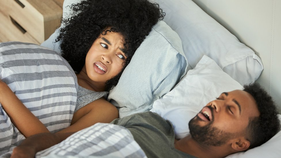 A women getting irritated with the man next to him snoring
