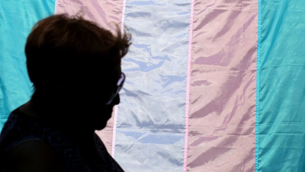 Osoba koja prolazi pored trans zastave