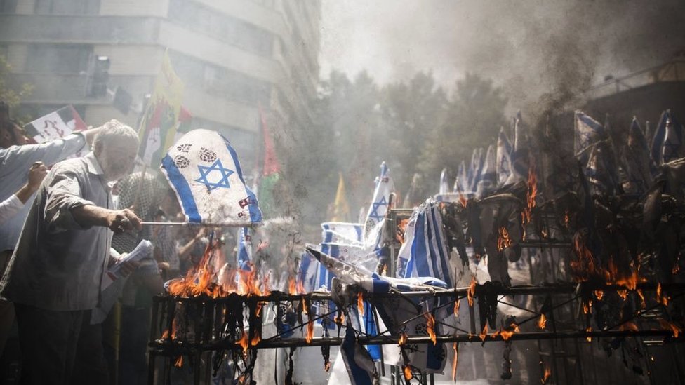 Men burn Israeli flags at a Tehran demonstration